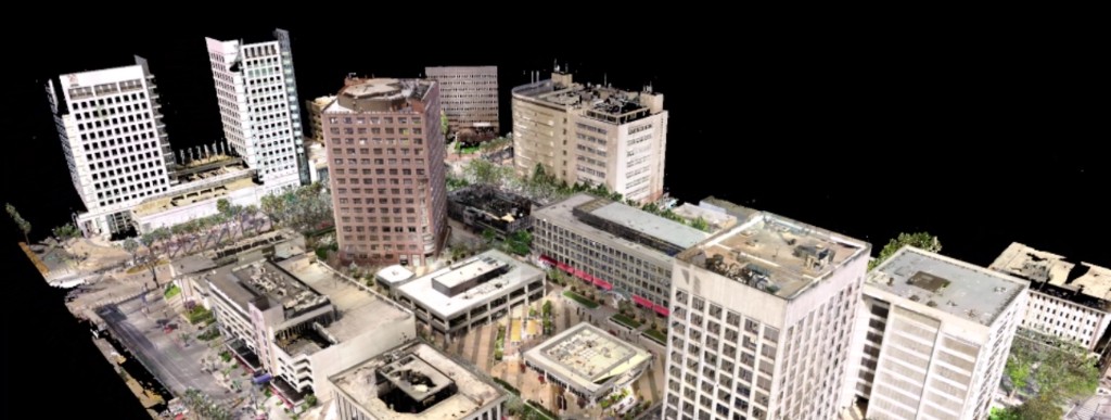 Aerial LiDAR point cloud view of a city block: buildings, streets, and urban context on a black background